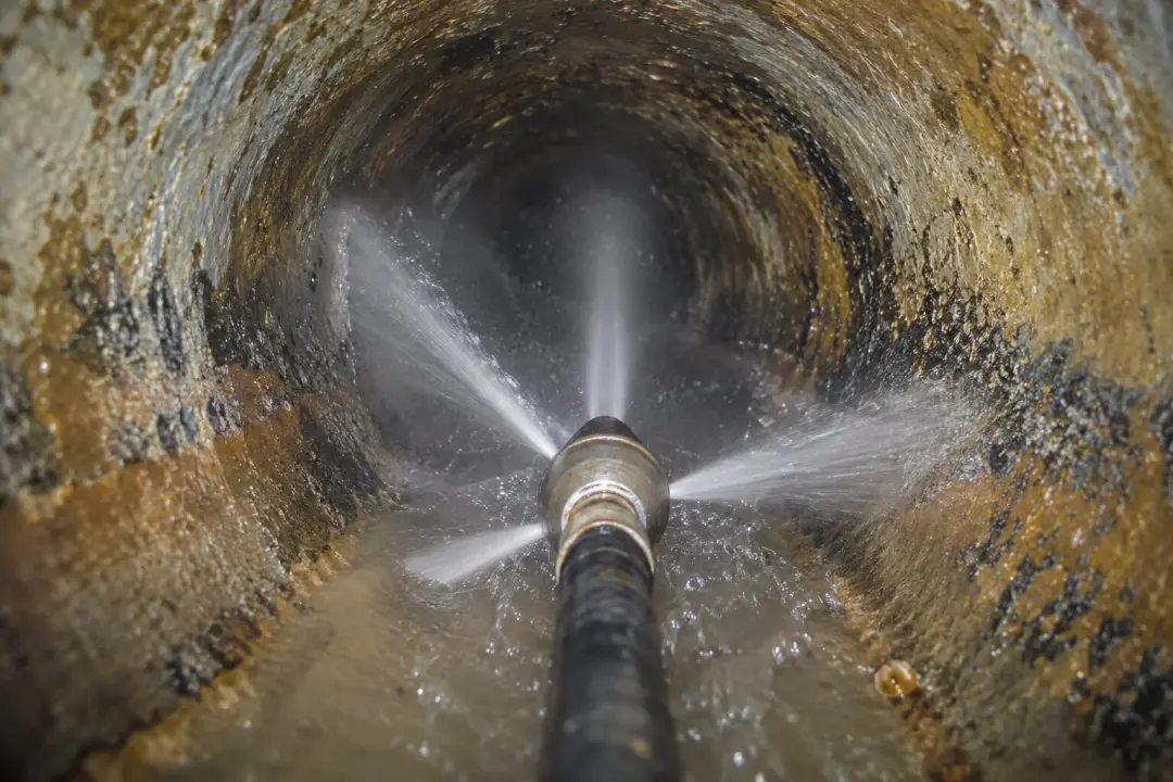 Jetting nozzle spraying water inside a drain pipe